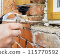 Window installation. The process of insulating windows with construction foam. A builder's hand seals the cracks between the building and the window frame. Construction and insulation of the building. 115770592