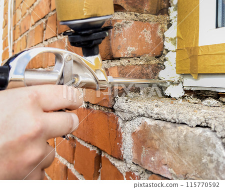 Window installation. The process of insulating windows with construction foam. A builder's hand seals the cracks between the building and the window frame. Construction and insulation of the building. Window installation. The process of insulating windows with construction foam. A builder's hand seals the cracks between the building and the window frame. Construction and insulation of the building. 115770592