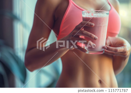 Woman in sportswear holding a glass of protein shake. Fitness healthy lifestyle 115771787