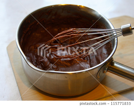 Chocolate cream for pie, dessert, sweets and cake in a saucepan with a whipping pattern on a wooden board on a white background. Pastry shop and pastry chef, cooking, kitchen worker, kitchen Chocolate cream for pie, dessert, sweets and cake in a saucepan with a whipping pattern on a wooden board on a white background. Pastry shop and pastry chef, cooking, kitchen worker, kitchen 115771833