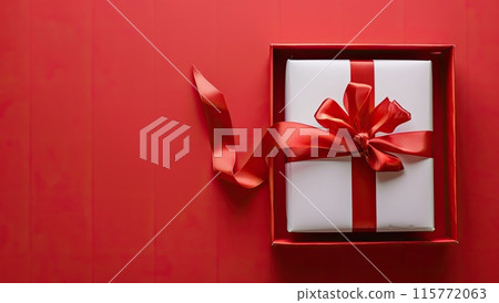 A white gift box with a red ribbon and bow against a red background A white gift box with a red ribbon and bow against a red background 115772063