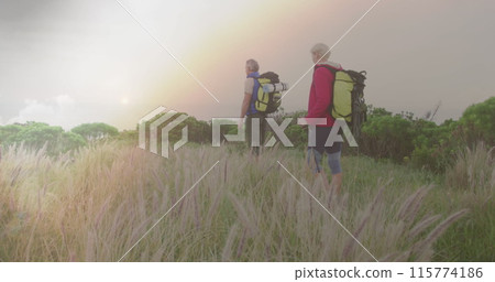 Caucasian senior couple hiking in countryside, over fast moving clouds and sunset Caucasian senior couple hiking in countryside, over fast moving clouds and sunset 115774186