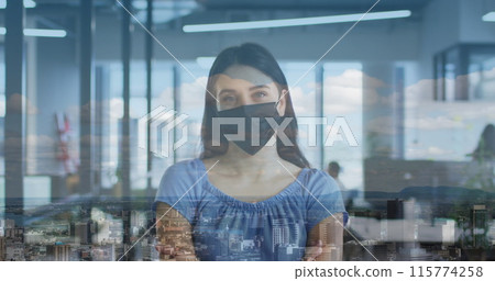 Image of cityscape over caucasian woman wearing face mask in office 115774258