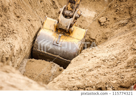 Working Excavator Tractor Digging A Trench at a Construction Site. Working Excavator Tractor Digging A Trench at a Construction Site. 115774321