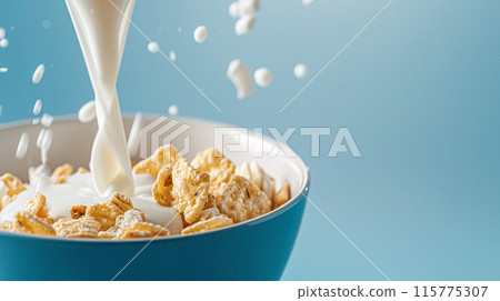 Pouring fresh milk into bowl of cereal on blue background on a sunny morning for breakfast 115775307