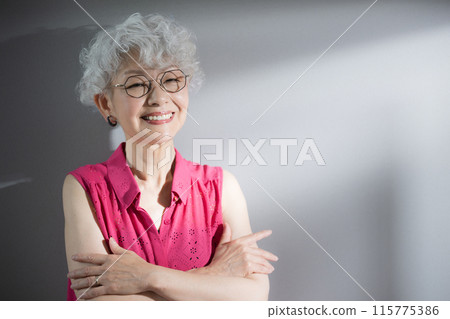 一個雙臂交叉看著鏡頭思考的灰髮女人 115775386