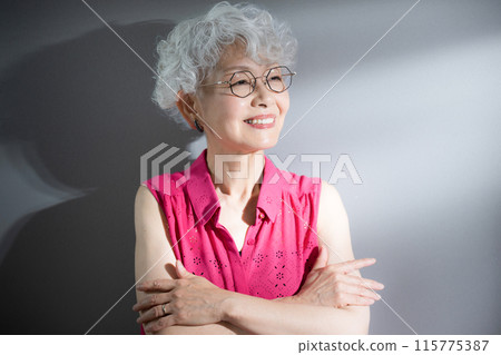 一位灰髮女子雙臂交叉，抬起頭，若有所思。 115775387
