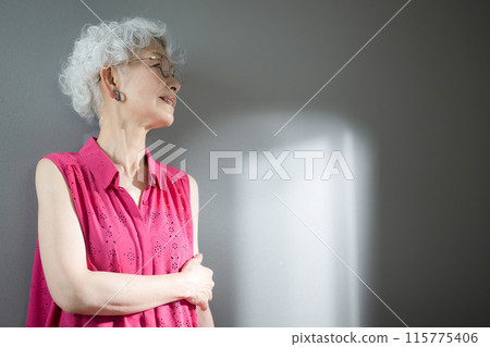 Profile of a gray-haired woman looking up, thinking with her arms folded Profile of a gray-haired woman looking up, thinking with her arms folded 115775406