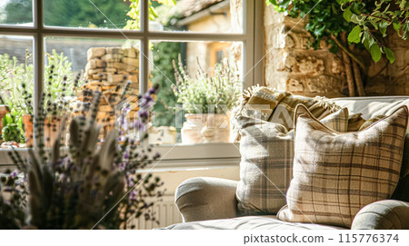English cottage interior, showcasing a plush armchair adorned with plaid cushions and a throw, positioned next to a large window 115776374