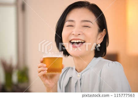 A middle-aged woman drinking beer with relish 115777563