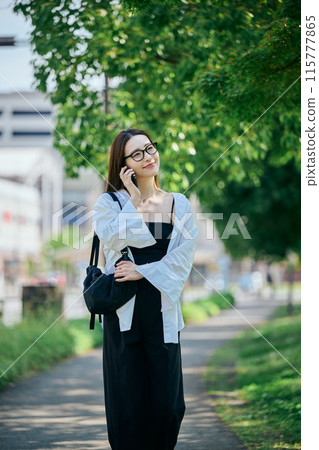A young woman walking while talking on her smartphone A young woman walking while talking on her smartphone 115777865