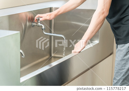 一名男子從水龍頭倒自來水，洗手，洗臉。 115778217
