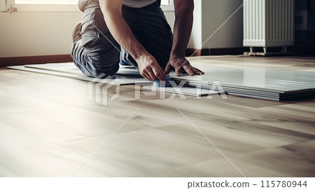 Focused hands lay down laminate flooring with precision and expertise. 115780944