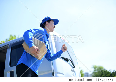 A male delivery driver running outdoors carrying packages 115782564