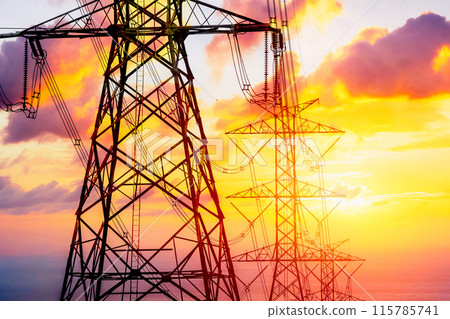 Electricity line on dusk orange sky, High voltage towers against the sunset background. Electricity line on dusk orange sky, High voltage towers against the sunset background. 115785741