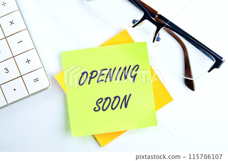 The words Opening soon text the inscription on the sticker on a light background next to the clock and calculator 115786107