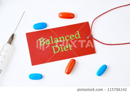 Balanced Diet text written on a red card on a light background with pills in the composition 115786142