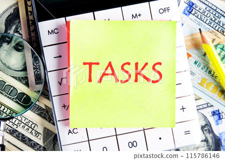 Business concept. The word Task written on a yellow sticker on the calculator against the background of dollar bills 115786146