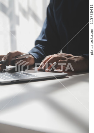 Cropped image of a young man working on his laptop in a coffee shop, rear view of business man hands busy using laptop at office desk, young male student typing on computer sitting at wooden table 115786411
