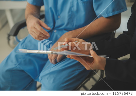 Midsection of female nurse checking blood pressure of woman sitting on wheelchair in clinic Midsection of female nurse checking blood pressure of woman sitting on wheelchair in clinic 115786472