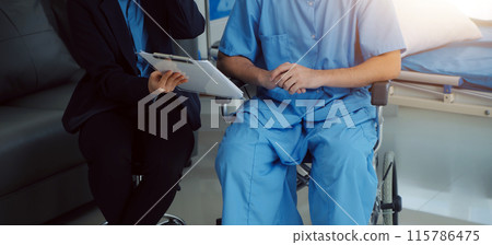 Midsection of female nurse checking blood pressure of woman sitting on wheelchair in clinic 115786475