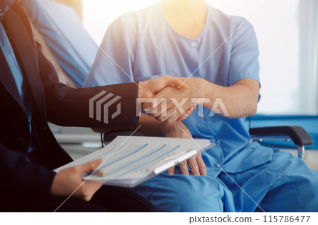 Midsection of female nurse checking blood pressure of woman sitting on wheelchair in clinic 115786477