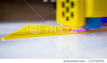 3D printer close up. A working 3D printer in process of printing object from molten plastic. 3D printer creating model by flowing liquid plastic from an extruder of printer. 3D printing technology 115788761