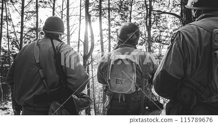 Group Of Usa Soldiers Armed Of Sturmgewehr 44 Or Assault Rifle 44. Back View On Re-enactors Dressed As American Infantry Soldier Watch For Bright Sun At Winter Day. Usa Army Soldiers Of World War Ii 115789676