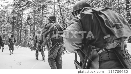 Heroes Of War. Re-enactors Dressed As American Infantry Soldier Marching Through Forest Road In Cold Winter Day. Group Of Usa Soldiers Marching Country Road. Usa Army Soldiers Of World War Ii 115789680