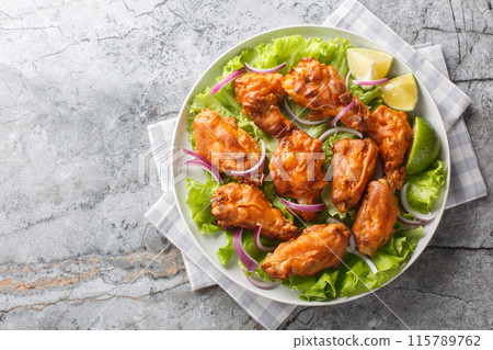 Asian style fried chicken is marinated with Tom Yam paste and then deep-fried to perfection closeup on the plate. Horizontal top view 115789762