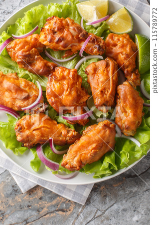 Fried Tom Yam Chicken is an Asian inspired Thai Style deep fried dish closeup on the plate on the table. Vertical top view 115789772