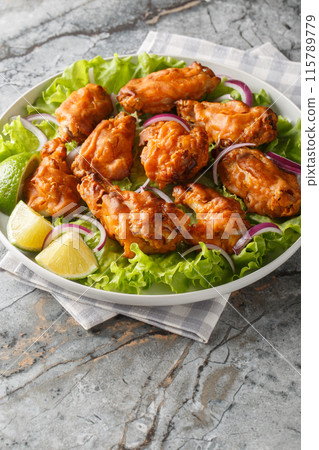 Thai Tom Yum Chicken served with onion, lime and lettuce closeup on the plate. Vertical 115789779
