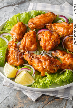 Tom Yum Fried Chicken, where the crispy crunch of delicious fried chicken meets with a fusion twist on Thailand tom yum flavors closeup on the plate. Vertical 115789781