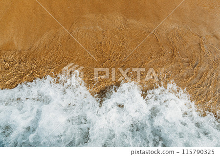 sandy beach with waves rolling in, creating a beautiful natural background. beige sand contrasts with ocean waves. concept for perfumes, smells, heat, freshness, coolness and other associations 115790325