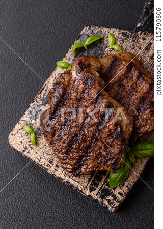 Fresh juicy delicious beef steak on a dark background Fresh juicy delicious beef steak on a dark background 115790806