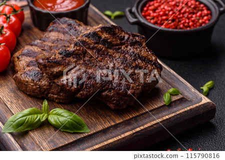 Fresh juicy delicious beef steak on a dark background Fresh juicy delicious beef steak on a dark background 115790816