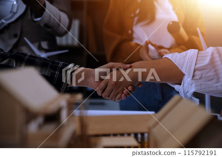Construction team shake hands greeting start new project plan behind yellow helmet on desk in office center to consults about their building project. in sun light 115792191