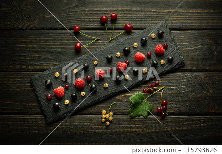 Ripe different berries on a black sorting board and on a dark vintage table served for breakfast Ripe different berries on a black sorting board and on a dark vintage table served for breakfast 115793626