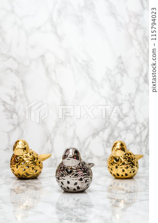 Golden and Silver Sparrow Figurines Arranged in a Row on a Marble Background with Copy Space 115794023