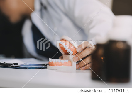 A dentist is using specialized dental equipment to inspect dentures to study the anatomy of the teeth before using the knowledge to treat patients, Dentures are being studied by oral specialists. 115795544