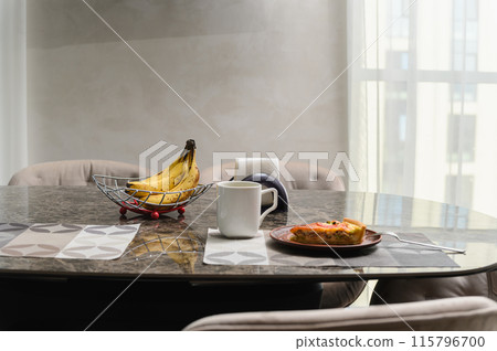 A modest breakfast of pie and a few bananas on a table in room interior. A modest breakfast of pie and a few bananas on a table in room interior. 115796700