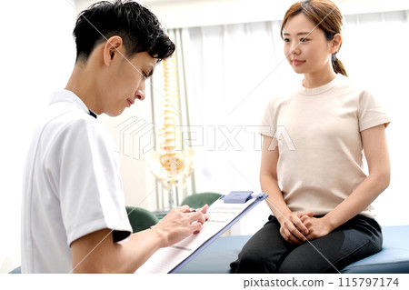 A man in a white coat smilingly interviewing a female patient A man in a white coat smilingly interviewing a female patient 115797174