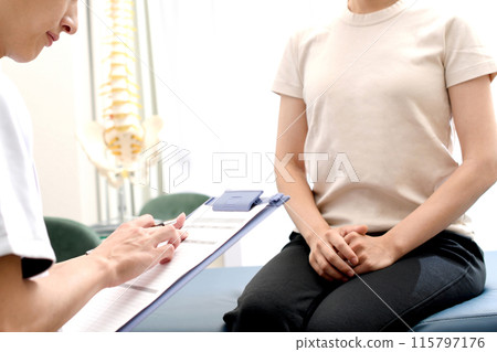 A man in a white coat smilingly interviewing a female patient A man in a white coat smilingly interviewing a female patient 115797176