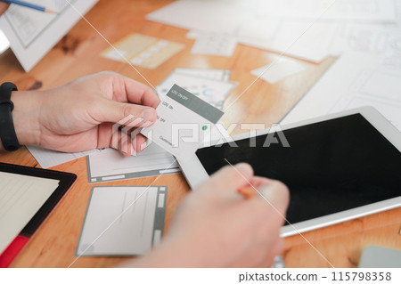 UX or UI designers designing on digital tablet and smartphone application layout prototype project. UX or UI designers designing on digital tablet and smartphone application layout prototype project. 115798358