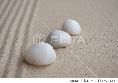 White zen stones line up on sand with customizable space for text. White zen stones line up on sand with customizable space for text. 115798483