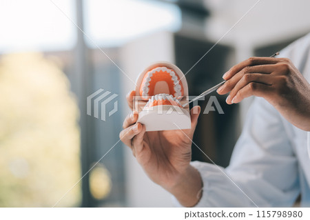 A dentist is using specialized dental equipment to inspect dentures to study the anatomy of the teeth before using the knowledge to treat patients, Dentures are being studied by oral specialists. 115798980