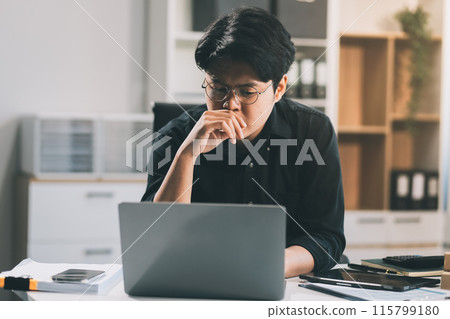 Frustrated Asian young businessman worker working on table in office. Busy employee worker people feel tired and headache from late work and overwork job document on computer desk at company workplace Frustrated Asian young businessman worker working on table in office. Busy employee worker people feel tired and headache from late work and overwork job document on computer desk at company workplace 115799180