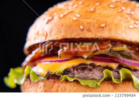 Burger with beef, cheese, vegetables on black plate. Dark Background. Close up. Burger with beef, cheese, vegetables on black plate. Dark Background. Close up. 115799484