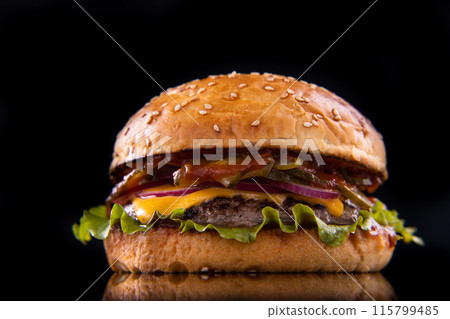 Burger with beef, cheese, vegetables on black plate. Dark Background. Close up. 115799485