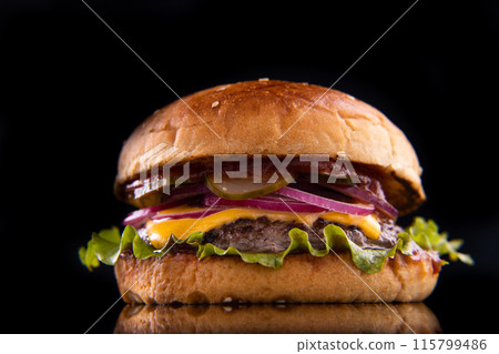 Burger with beef, cheese, vegetables on black plate. Dark Background. Close up. 115799486